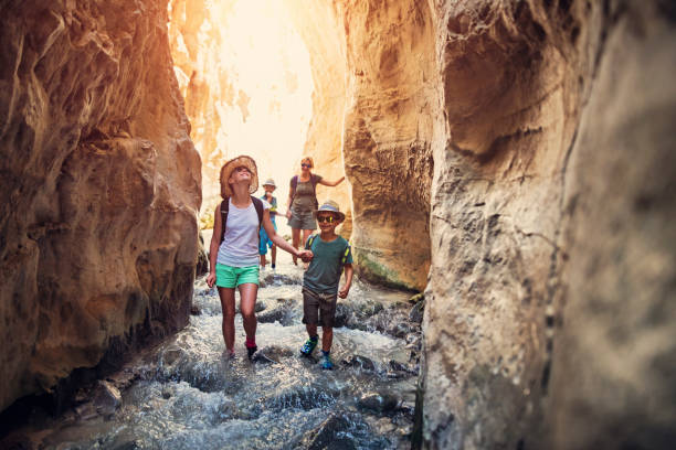 Family hiking through rivier in Andalusia, Spain Mother and kids hiking through river Rio Chillar in Andalusia, Spain. They are walking in the mountain river flowing through the narrow canyon.

 canyon photos stock pictures, royalty-free photos & images