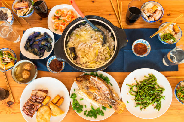 A large hotpot and a whole cooked fish among the dishes prepared for a traditional Chinese family meal.