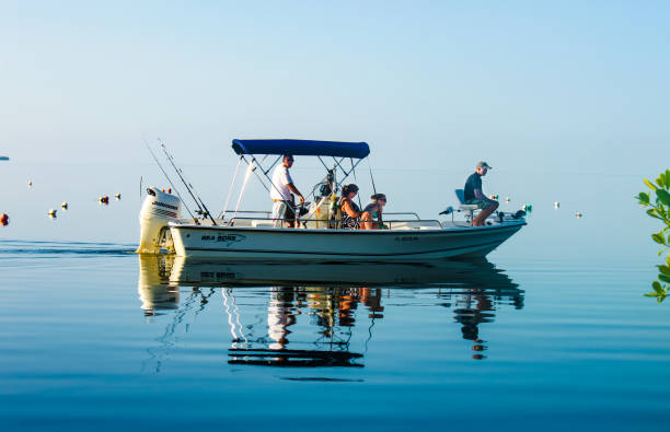 Family in fishing boat on very calm water where the ocean blends into the sky stock photo