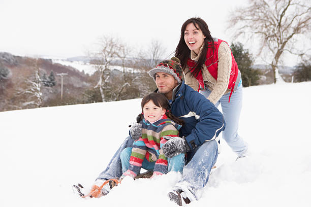 Family In Snow Riding On Sledge Having Fun