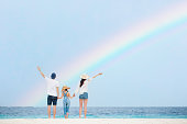 虹のビーチで空を見上げる家族