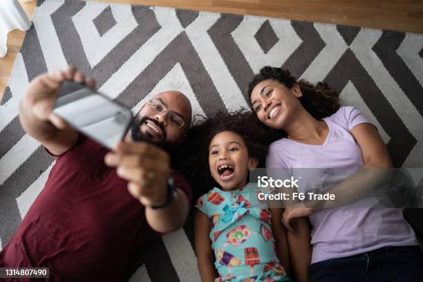 Family lying on the floor taking selfies or filming at home