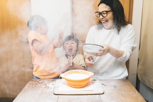 Flour is swirling in the air and Asian family are surprised  while kneading flour.