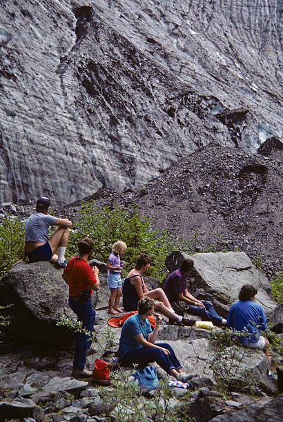 Family of Hikers Rests Near the Carbon Glacier's Snout Mount Rainier National Park, Washington, USA - August 29, 1984: A family of hikers rests beside large rocks and looks at the snout of the Carbon Glacier. jeff goulden people stock pictures, royalty-free photos & images