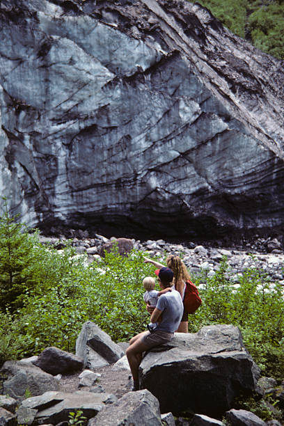 Family of Hikers Rests Near the Carbon Glacier's Snout Mount Rainier National Park, Washington, USA - August 29, 1984: A family of three hikers rests beside large rocks and looks at the snout of the Carbon Glacier. jeff goulden rock formation stock pictures, royalty-free photos & images