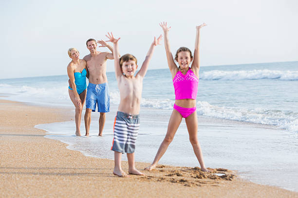 Family on the beach Parents watching their children play on the beach.  Focus on parents. mother and child stock pictures, royalty-free photos & images