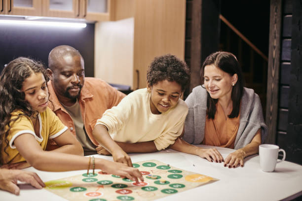 Family playing board game together Happy parents sitting at the table and playing with children in board game at home board game photos stock pictures, royalty-free photos & images