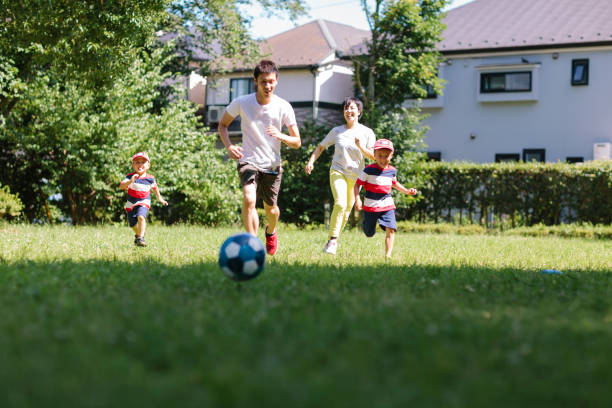 日本の家族が東京の公共公園でサッカーをしている。
