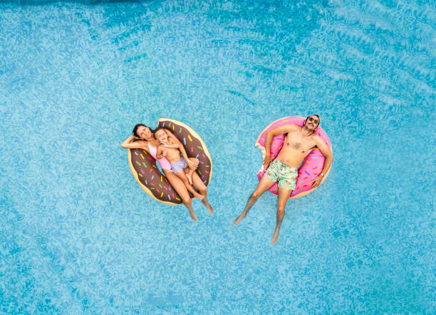 Family relaxing at swimming pool Family relaxing at swimming pool floating on water stock pictures, royalty-free photos & images