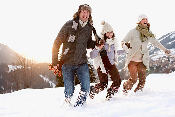 family running outdoors in snow - happy couple cold stockfoto's en -beelden