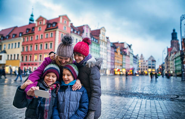 Family sightseeing city of Wroclaw in autumn Mother with three kids taking selfie in Wroclaw main square. Family is sightseeing the city on cold autumn day evening. Sightseeing is fun even in the bad weather! wroclaw stock pictures, royalty-free photos & images