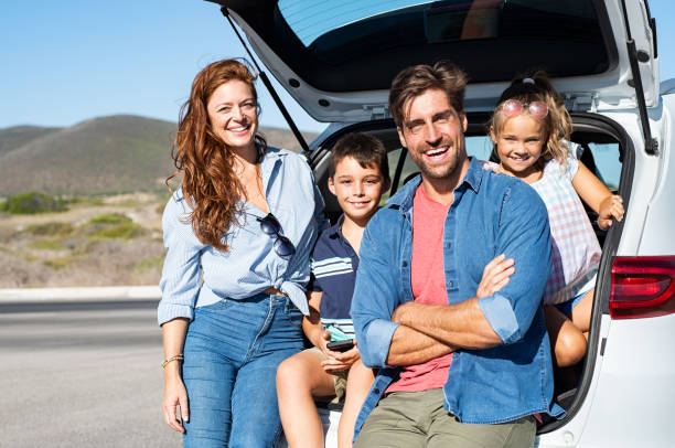 Family sitting in car trunk Smiling family with two kids sitting in car trunk and looking at camera. Happy children enjoying with mother and father a trip while sitting in car back. Portrait of cheerful young family on a road trip in their auto. car trunk photos stock pictures, royalty-free photos & images