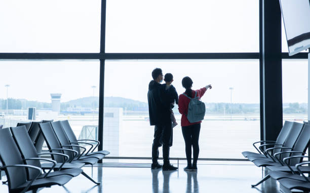 Family  standing near window in airport before boarding stock photo