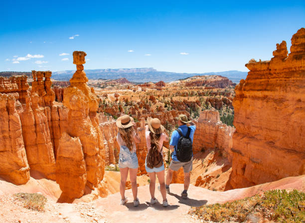 Family standing  on top of  mountain looking at beautiful red mountains. stock photo