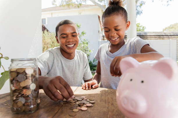 Family throwing coins into a piggy bank together. stock photo