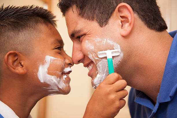 Family Time! Single dad and son "shaving" in home bathroom. stock photo