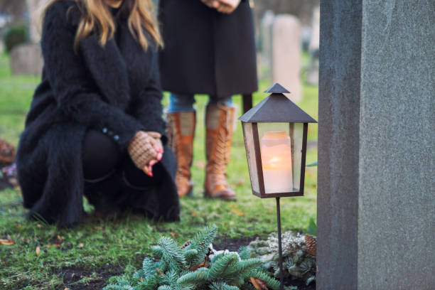 Family visiting a grave and lighting a candle stock photo