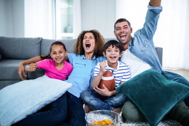 familie kijken american football-wedstrijd op televisie - kijken naar stockfoto's en -beelden