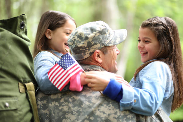 Family welcomes home USA army soldier. Family welcomes home a USA army soldier.  The children excitedly hug father holding American flags. veterans returning home stock pictures, royalty-free photos & images