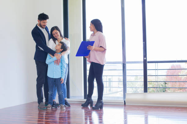 familia con una vendedora de bienes raíces mirando una nueva casa para comprar - latin family fotografías e imágenes de stock