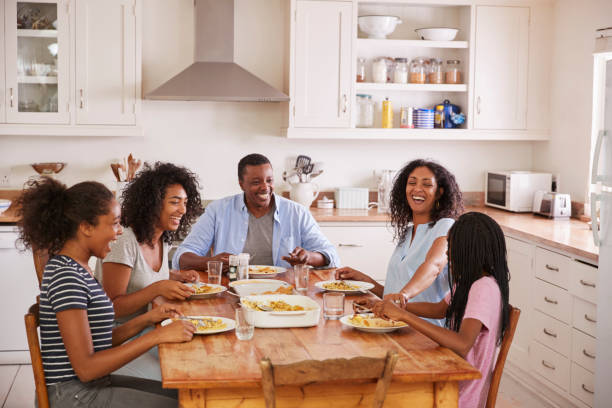 familj med tonårsbarn äter måltid i köket - family dinner bildbanksfoton och bilder