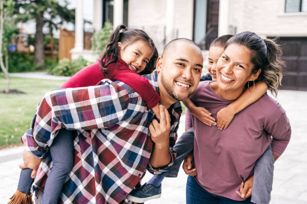 Family with two kids looking at camera Parents carrying children piggyback outdoor filipino family stock pictures, royalty-free photos & images
