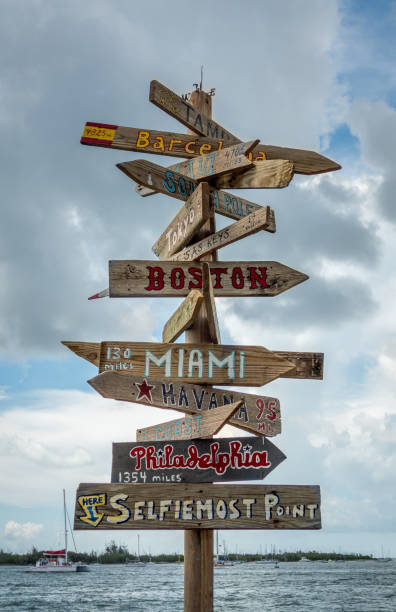 Famous Key West habour sign post with distances to major cities aka Selfiemost Point Famous Key West habour sign post with distances to major american and international cities, also known as Selfiemost Point. Cloudy background with sea visible, No people. florida beaches map stock pictures, royalty-free photos & images