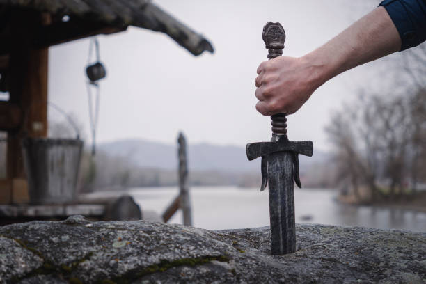 famous sword excalibur of King Arthur stuck in rock. Edged weapons from the legend Pro king Arthur. stock photo