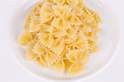 Farfalle pasta on a plate. Isolated over white background. Close-up.