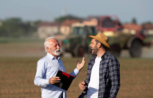 Farmer and insurance agent talking in agricultural field in spring stock photo