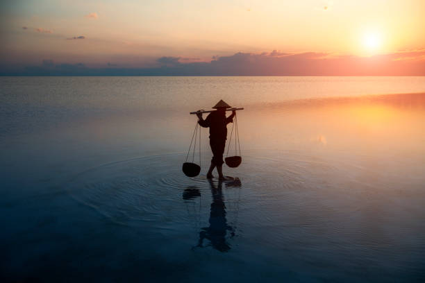Farmer carrying baskets on the water. stock photo