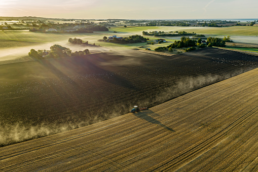 An aerial view of a farmer plowing in a farm field with a hoe.
