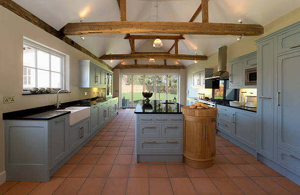 Farmhouse Kitchen a beautiful farmhouse kitchen in a fully restored and rebuilt farm. Old, weathered oak beams support the roof and ceiling. Brand new terracotta flooring compliments the pastel toned powder blue cupboards and large kitchen island. This is a modern featured kitchen with all the appliances but constructed in a traditional style and being faithful to the 500 year old building. roof beam stock pictures, royalty-free photos & images