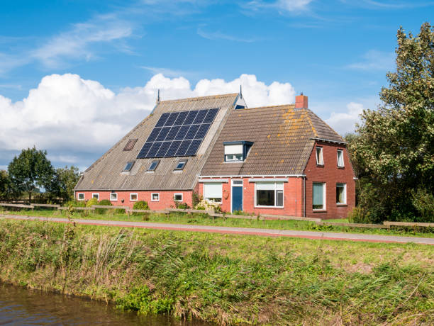 Farmhouse with solar panels on roof by Dokkumer Ee canal in Friesland, Netherlands stock photo