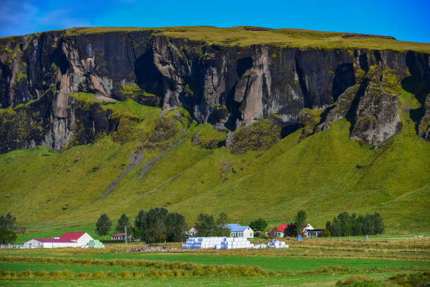 Farms below volcanic cliffs in the south coast of Iceland stock photo