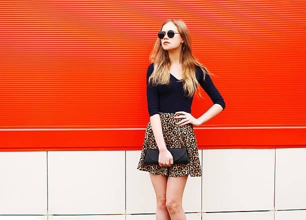 Fashion beautiful woman in leopard skirt sunglasses handbag clutch posing stock photo