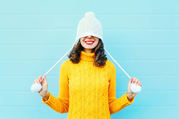 Fashion happy young woman in knitted hat sweater having fun Fashion happy young woman in knitted hat and sweater having fun over colorful blue background sweater photos stock pictures, royalty-free photos & images