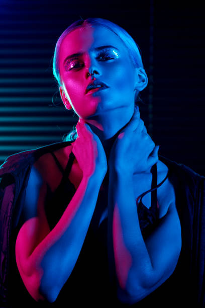 Fashion model blonde woman in colorful bright neon lights posing in studio. stock photo