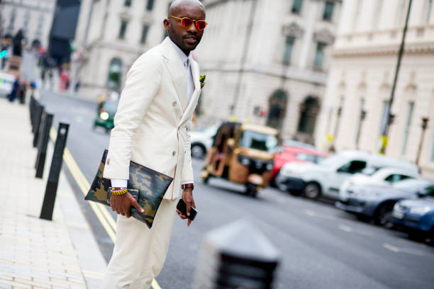 A Fashionable man attends London Collection Men fashion week in London A very stylish man in a white suit and reflective shades  attends London Collection Men in London. mens fashion stock pictures, royalty-free photos & images