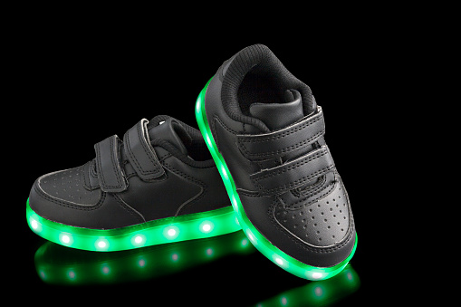 Fashionable sneakers with LED lighting on black backgrounds