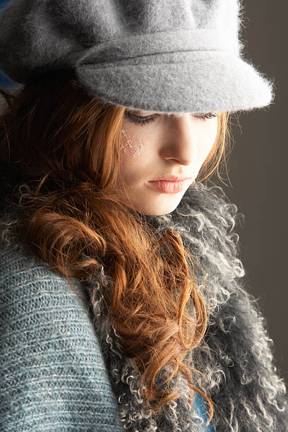 Fashionable Teenage Girl Wearing Cap And Knitwear In Studio Looking...