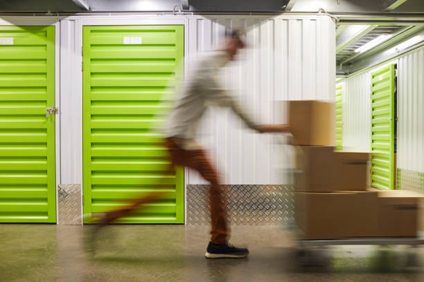 Fast Delivery to Storage Unit Blurred motion shot of unrecognizable man pushing cart with boxes while running in self storage facility, copy space self storage stock pictures, royalty-free photos & images