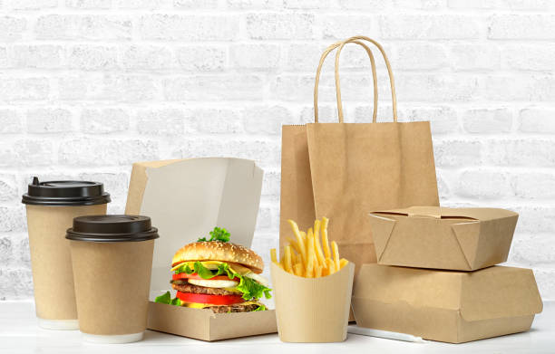 Fast food big lunch set. Fast food big lunch set of tasty hamburger, french fries, paper coffee cups, brown paper bag and box on the table on white brick wall background take out food stock pictures, royalty-free photos & images