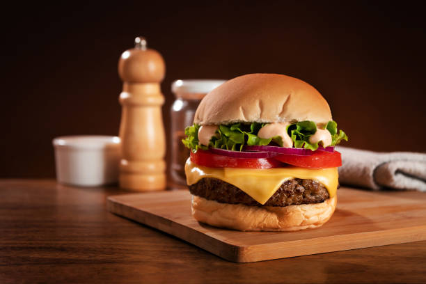 Fast food restaurant hamburger on cutting board Fast-food restaurant burger on bamboo board bread photos stock pictures, royalty-free photos & images