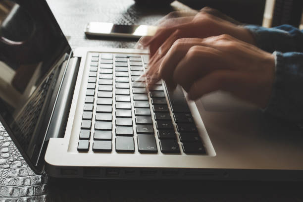 Fast typing woman on laptop. Blurred hands typing stock photo