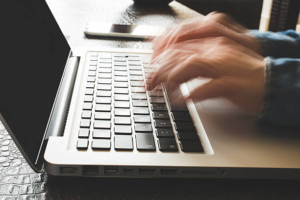 Fast typing woman on laptop. Blurred hands typing stock photo