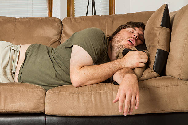 fat guy passed out hard on the couch stock photo