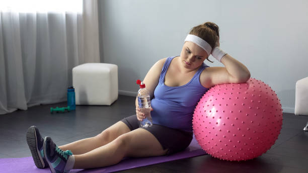 Fat lady depressed about her weight unsuccessful workout restoring water balance stock photo