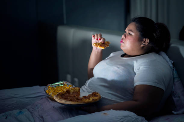 fat woman eating pizza on bed - come e sente imagens e fotografias de stock