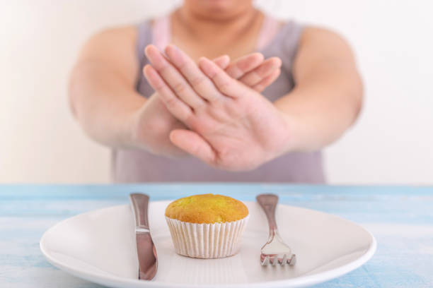 太った女性は、カップケーキや不健康な食品を拒否します。医療コンセプト。 - 断食 ストックフォトと画像